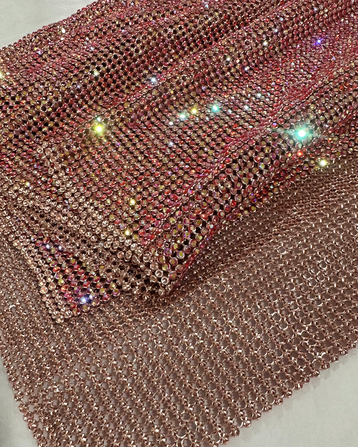 Close-up of light siam AB crystal mesh fabric with 2mm crystals in rose gold casing