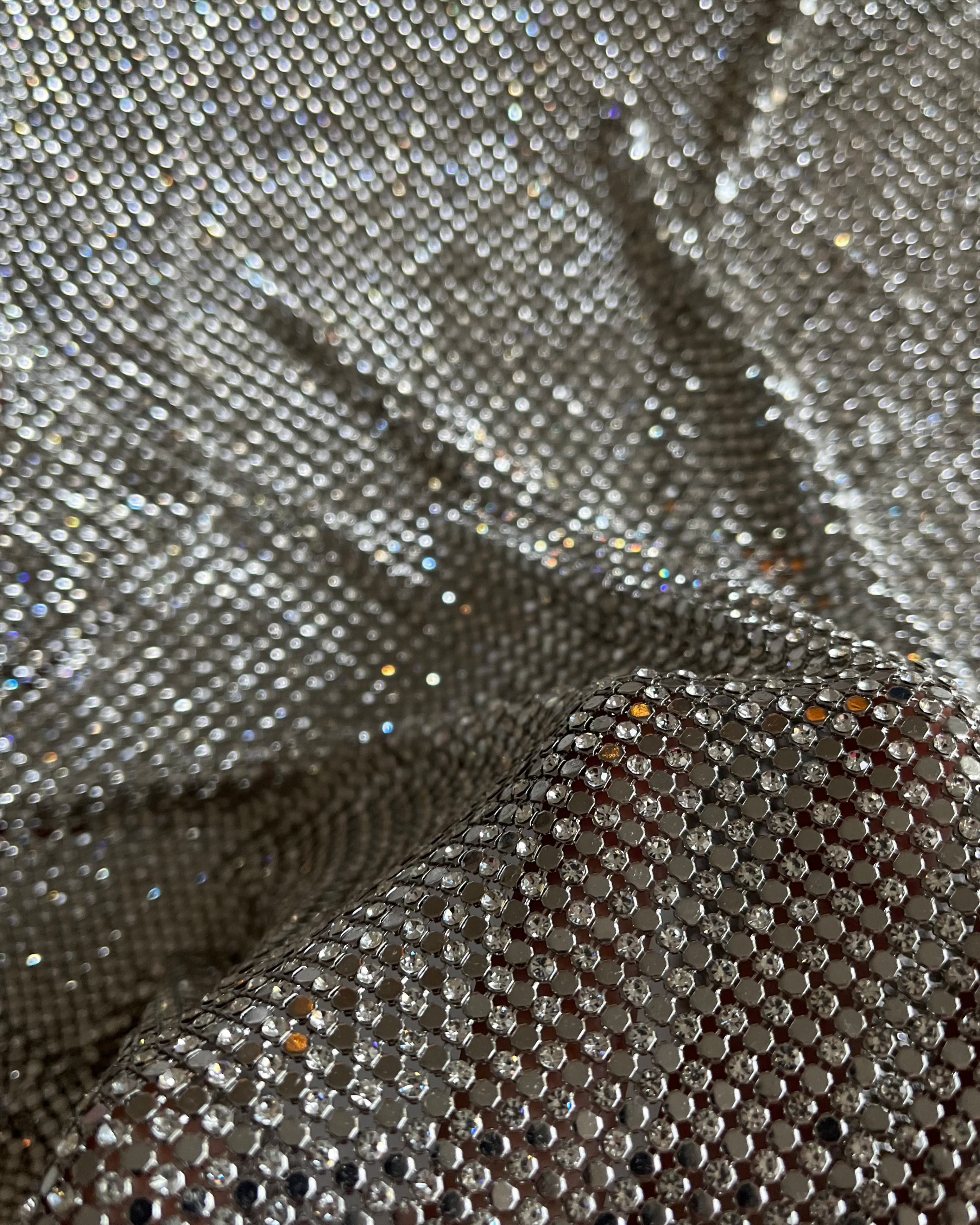 A luxurious chainmail silver platinum fabric adorned with high-quality, dazzling silver rhinestones, creating a stunning and radiant surface