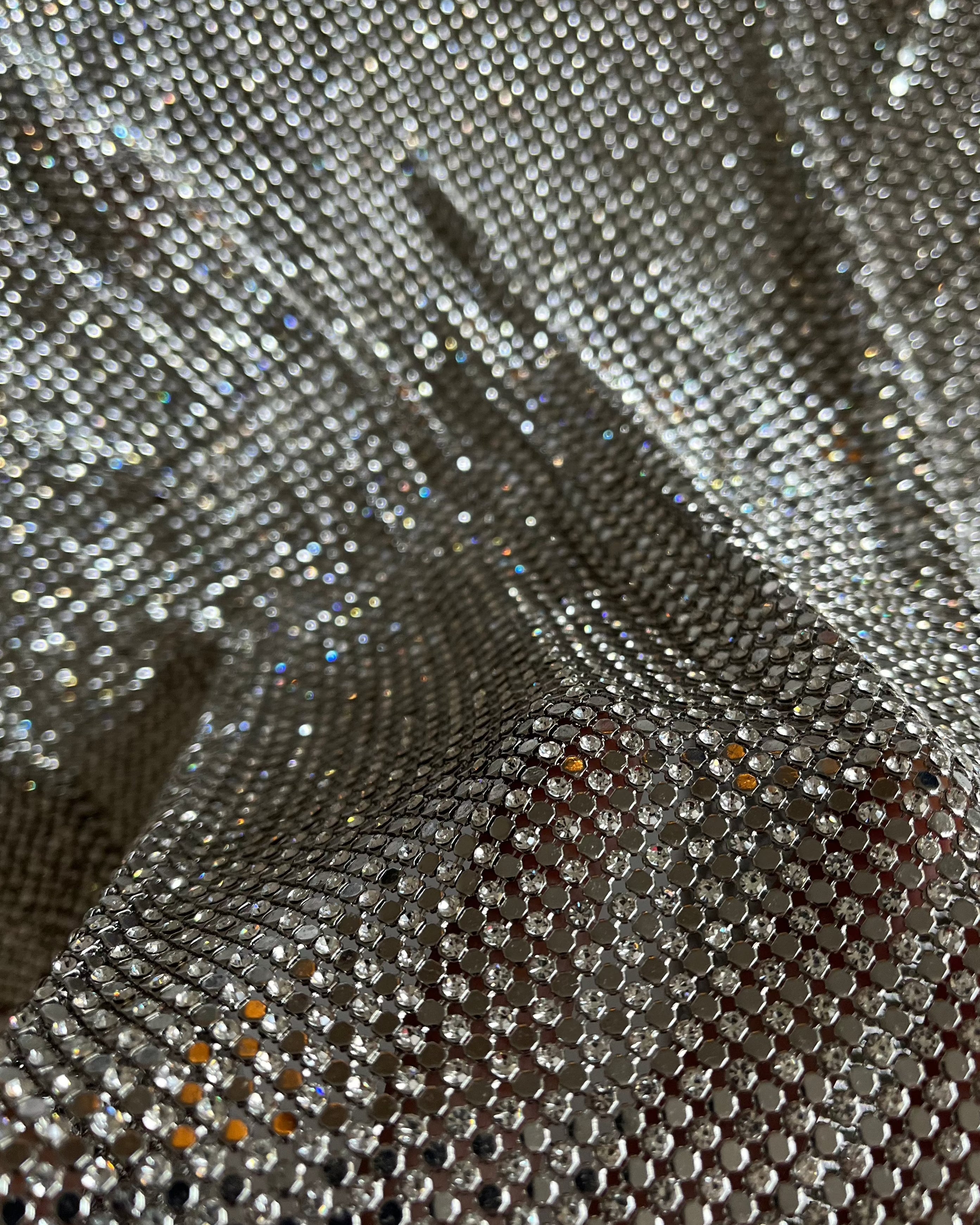 A luxurious chainmail silver platinum fabric adorned with high-quality, dazzling silver rhinestones, creating a stunning and radiant surface