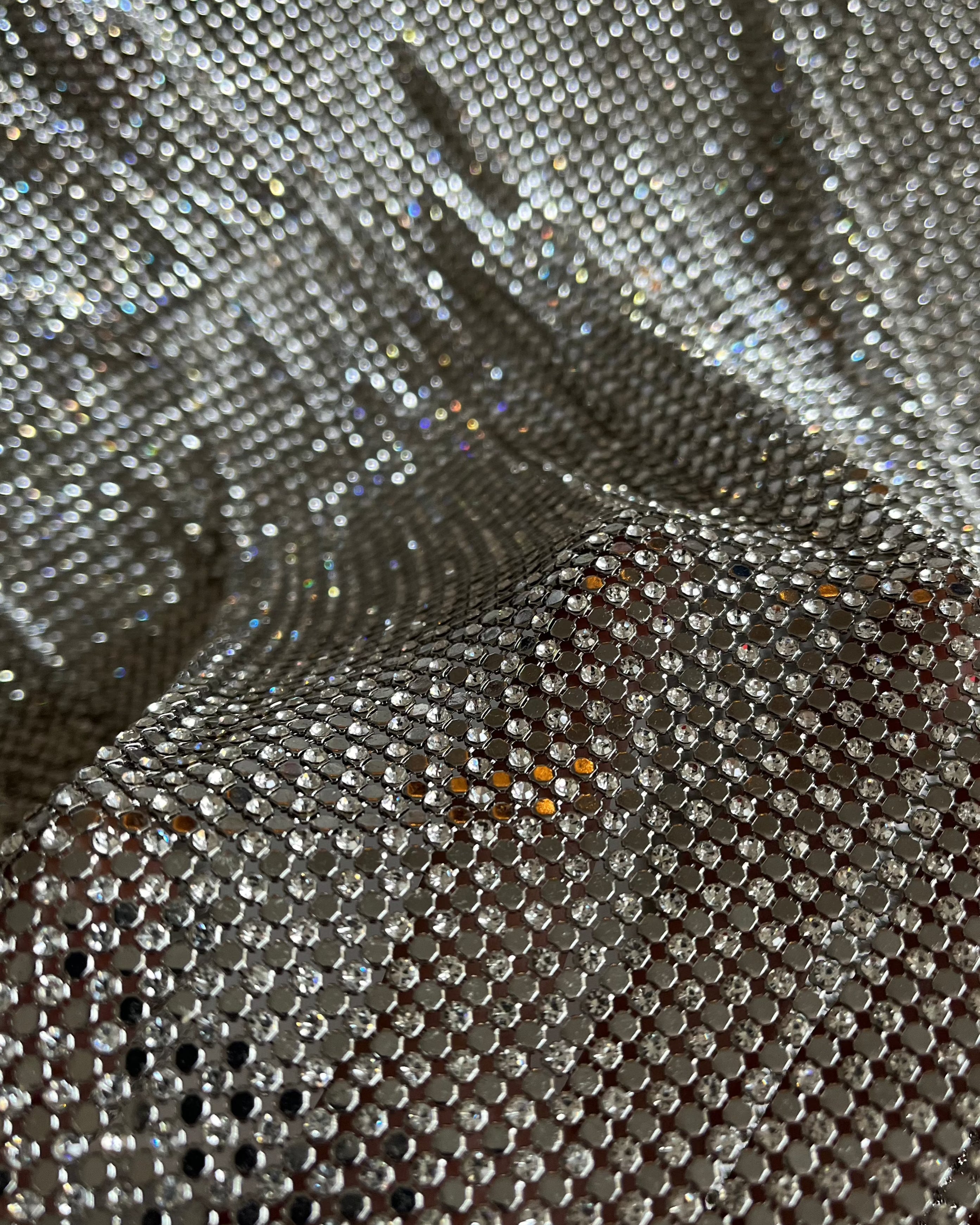 A luxurious chainmail silver platinum fabric adorned with high-quality, dazzling silver rhinestones, creating a stunning and radiant surface