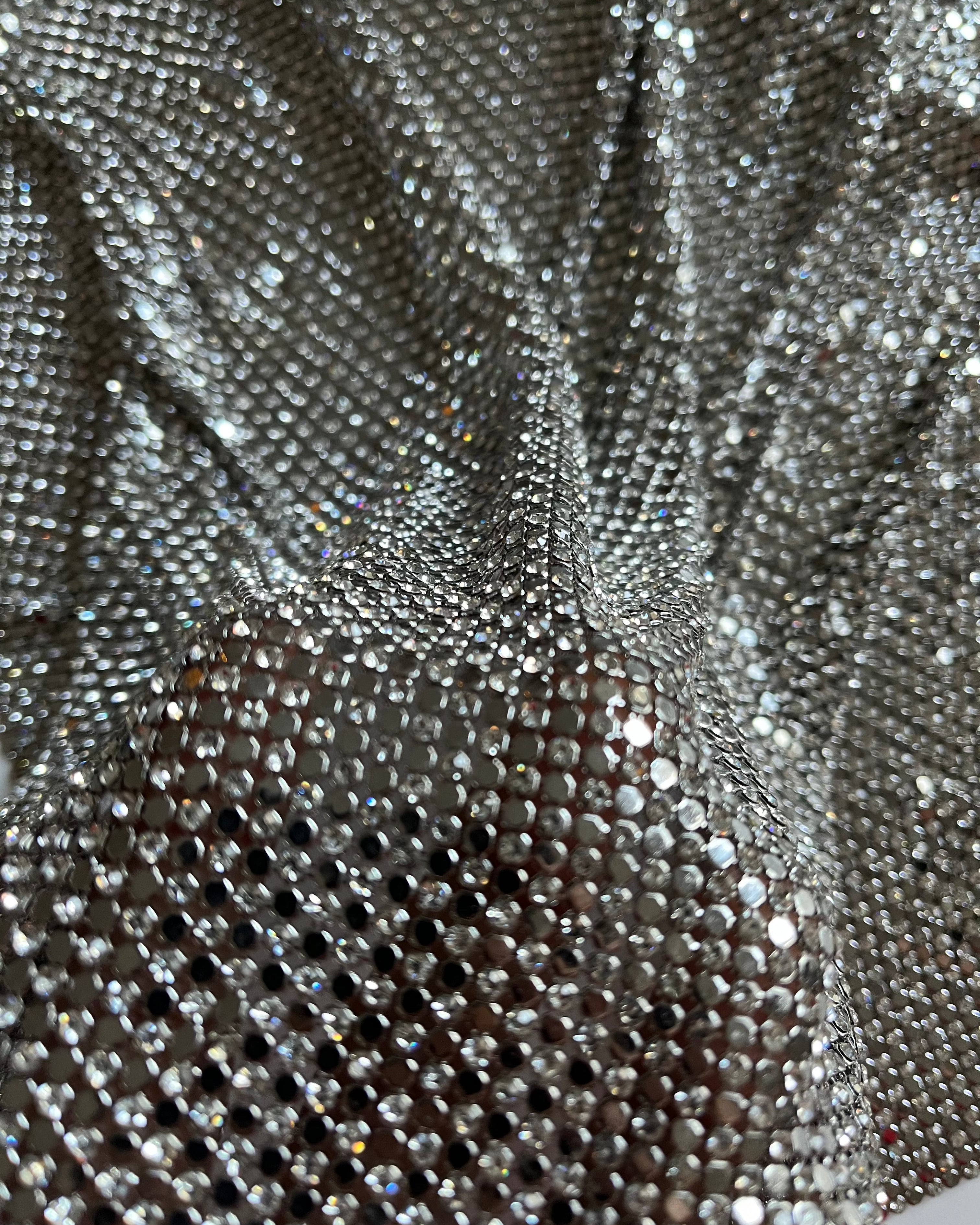 A luxurious chainmail silver platinum fabric adorned with high-quality, dazzling silver rhinestones, creating a stunning and radiant surface